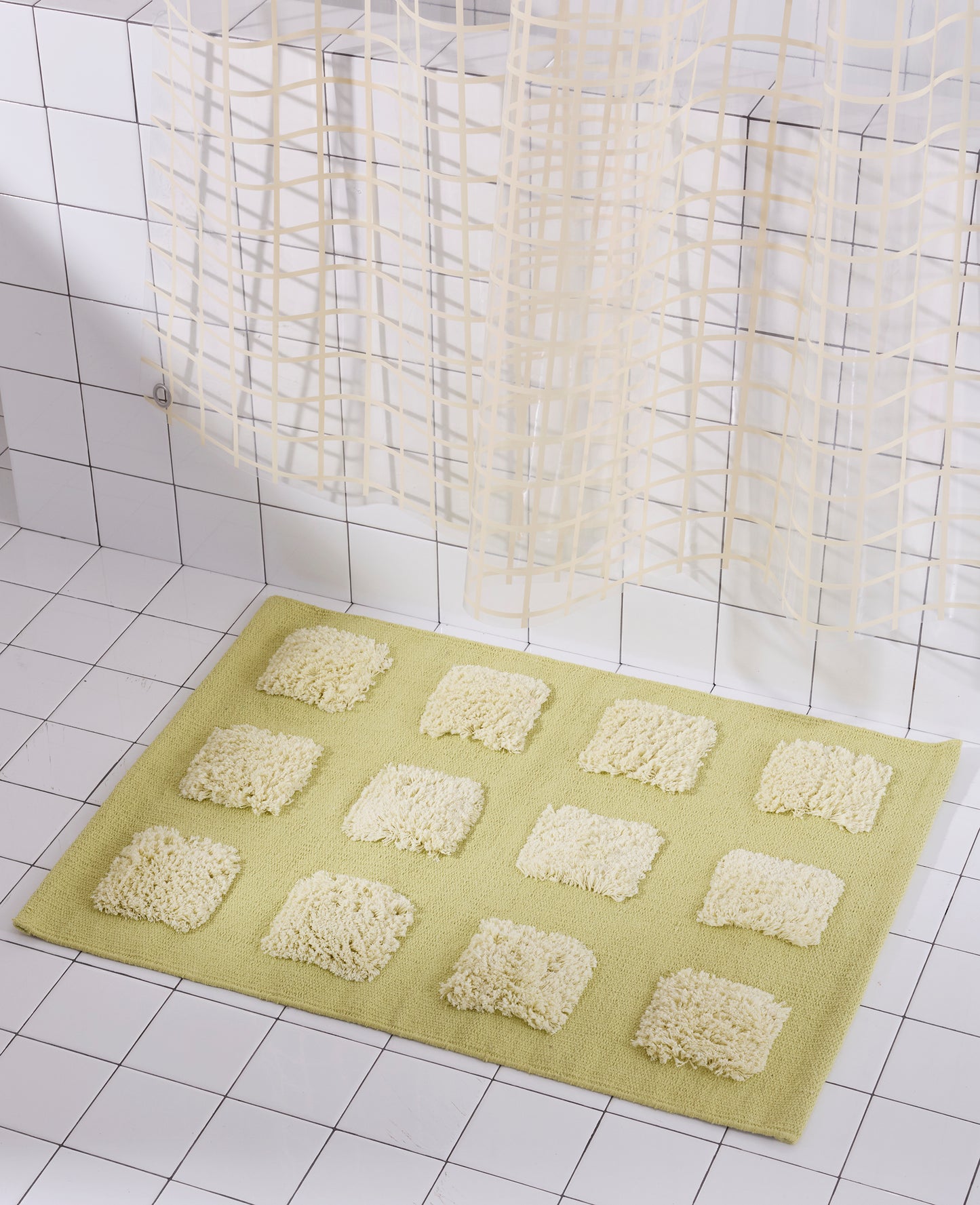 A yellow/olive natural woven bath mat featuring twelve raised, natural-colored textured rectangular tufts arranged in a 4-by-3 grid pattern.