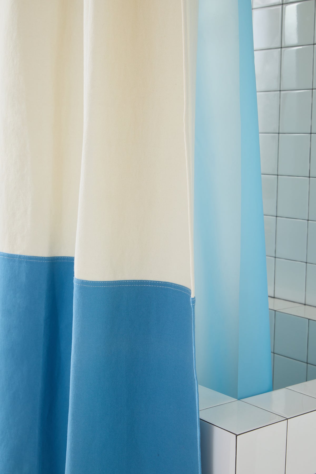 Close-up view of Orient Atlantic colorblock curtain hanging next to tiled walls