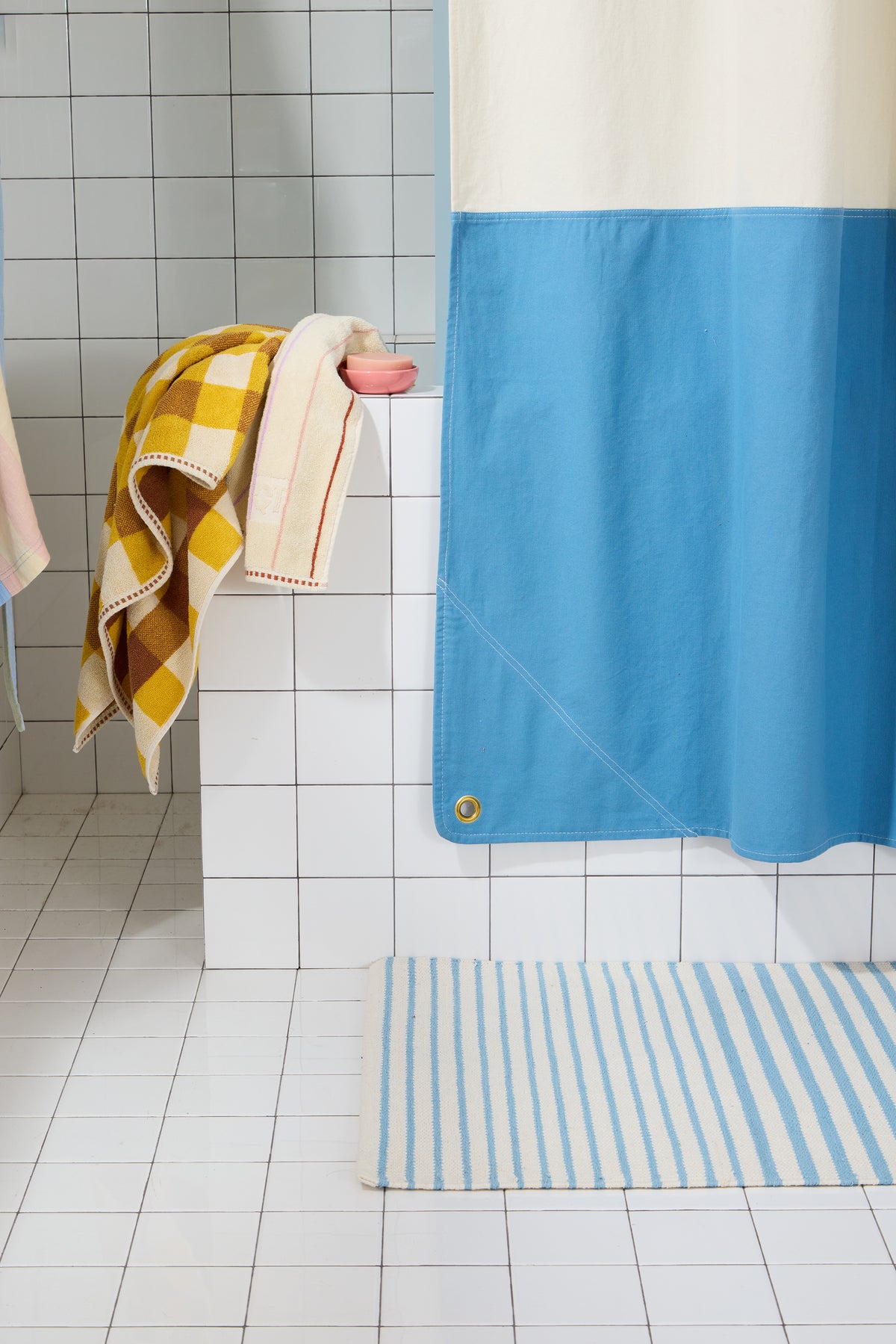 Bottom corner detail of Orient Atlantic colorblock shower curtain with brass grommet.