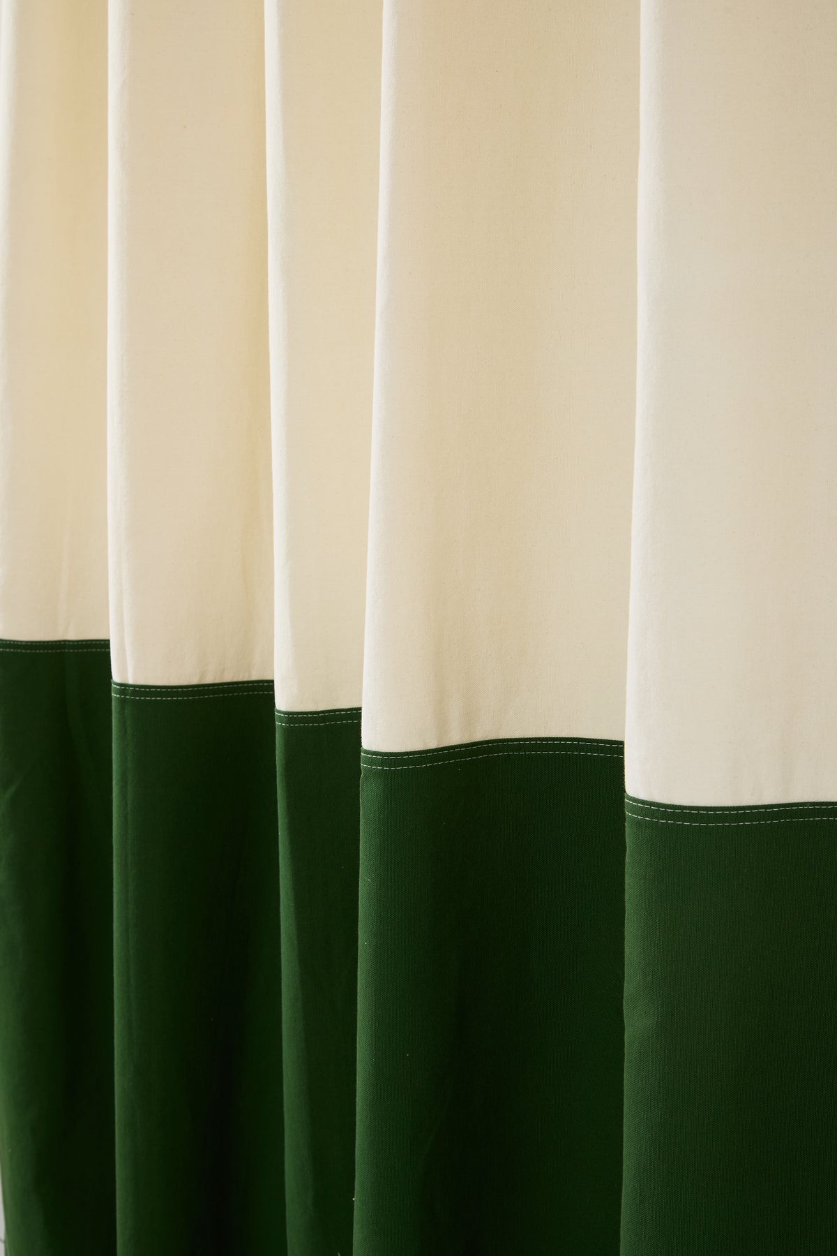 Close-up of the stitched seam on a cream and pine green colorblock shower curtain.
