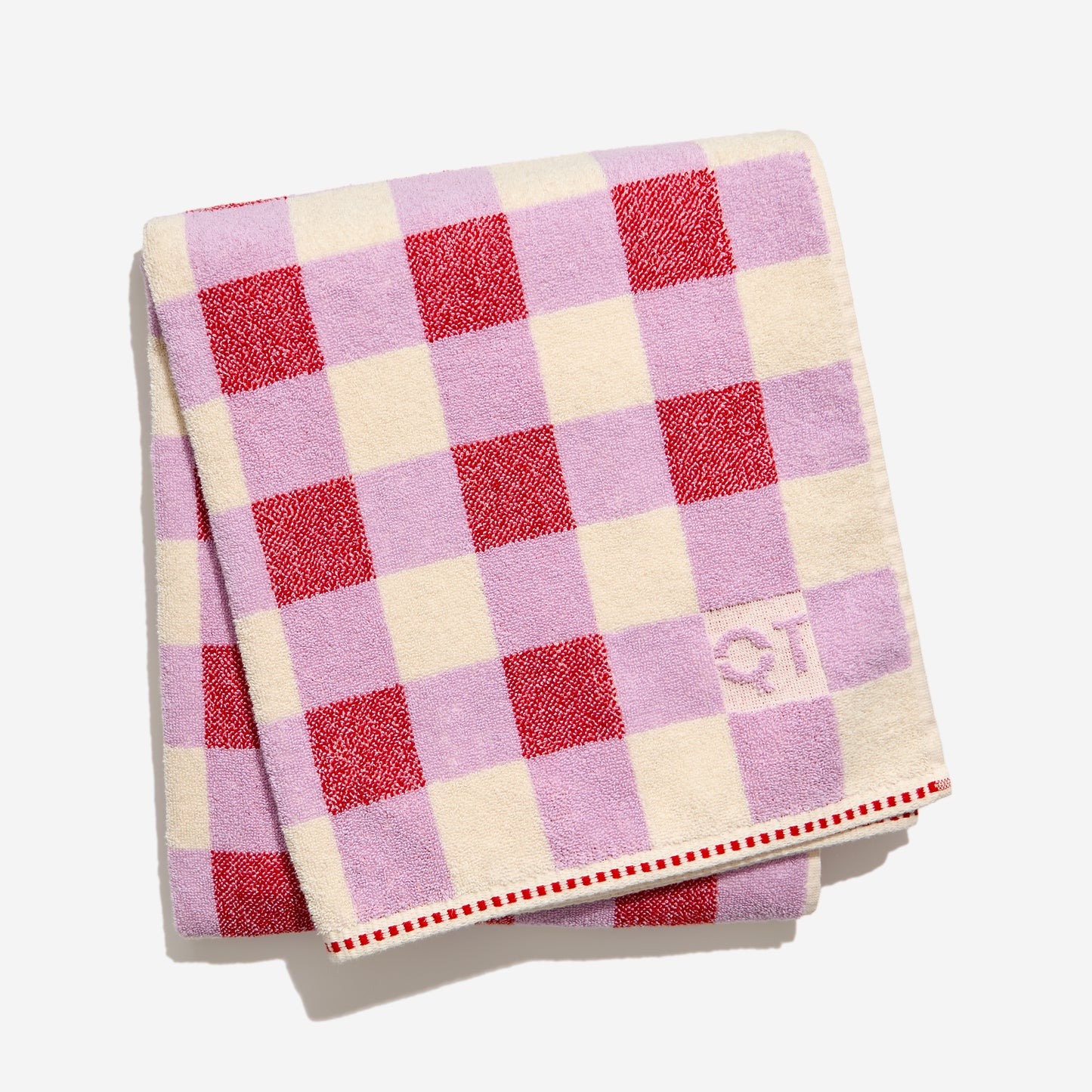 Checkered towel with red and purple and cream squares on a white background