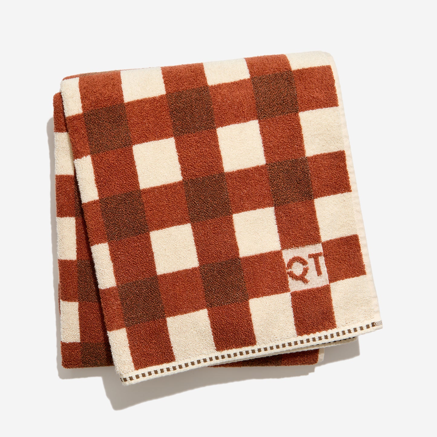 Folded checkered towel with brown  and clay and beige squares on a white background
