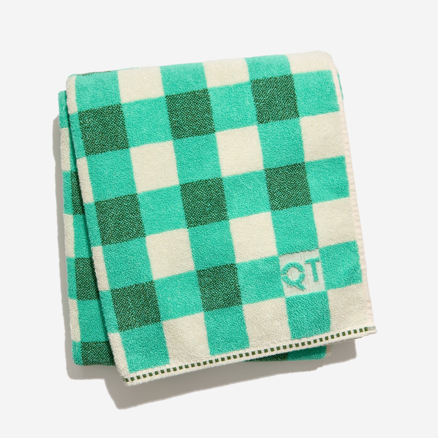 Folded green , teal and cream checkered towel with a logo on a light gray background