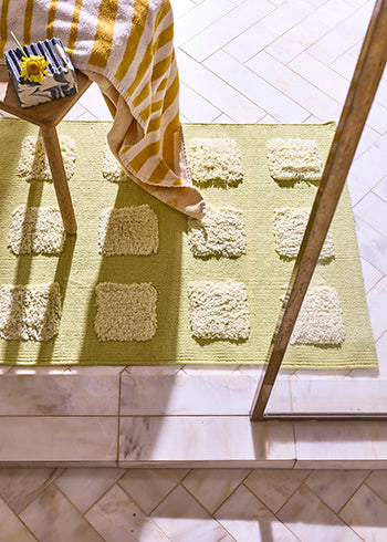 lime green mat wtih square texture in cream marble bathroom. 