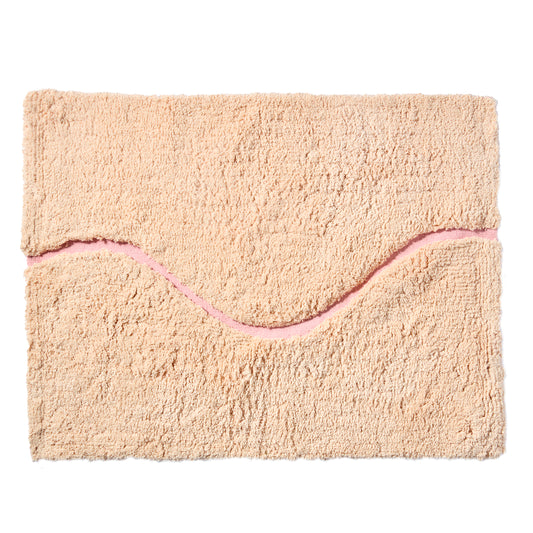 Peach bath mat in 21"x31" size with pink curvy path stripe contrast shot against a white backdrop.