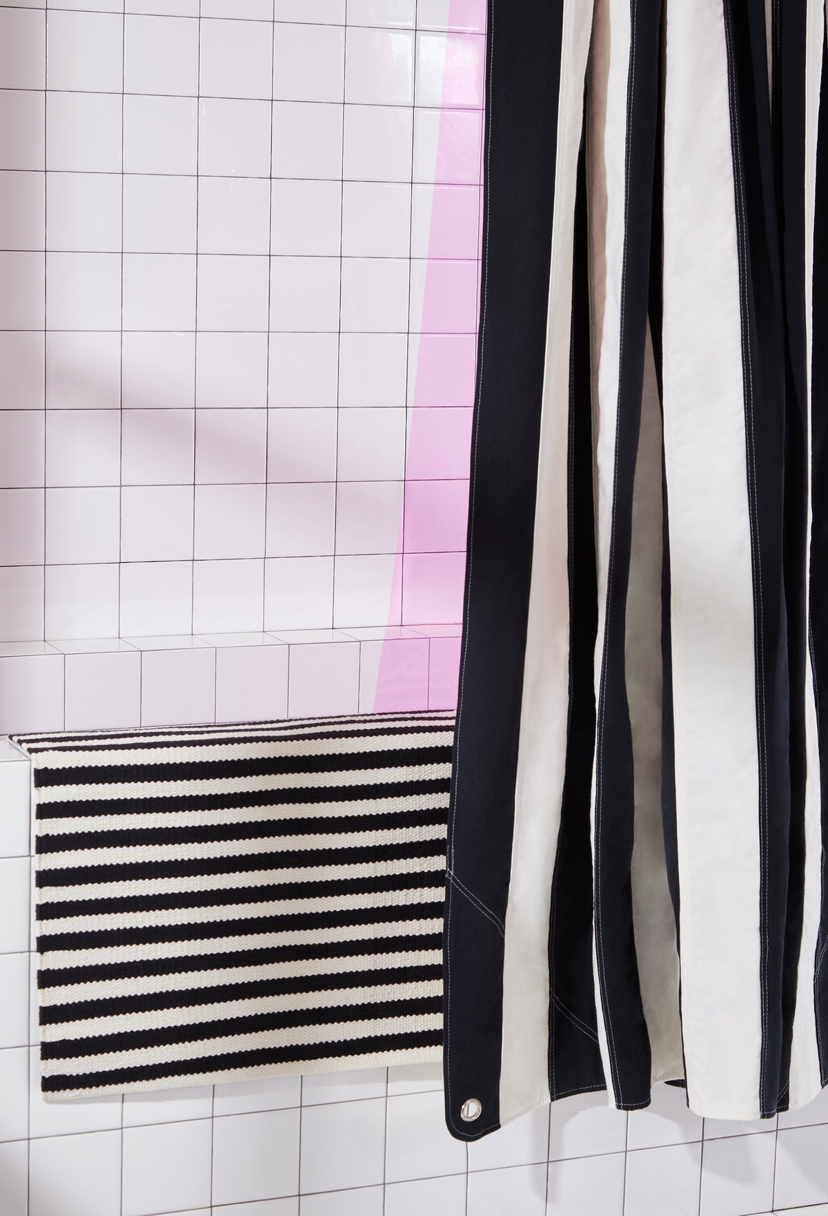black and white striped rug and curtain on white tiled background with hot pink liner. 