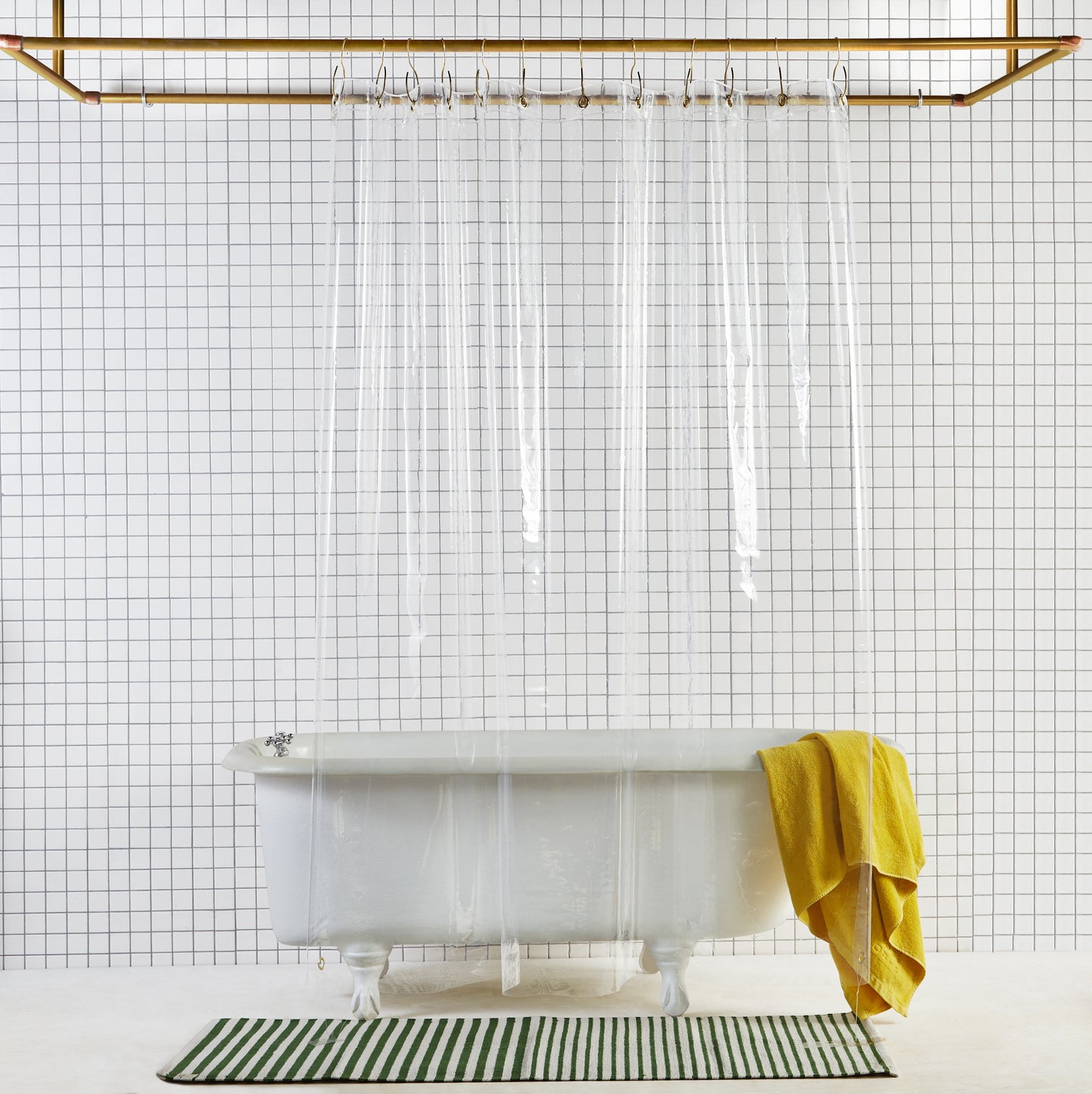 Sun shower curtain in air hanging over bathtub styled in a white tiled bathroom 